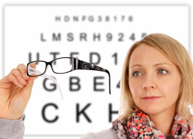Image Credit: mariok / 123RF Stock Woman holding spectacles in front of reading chart